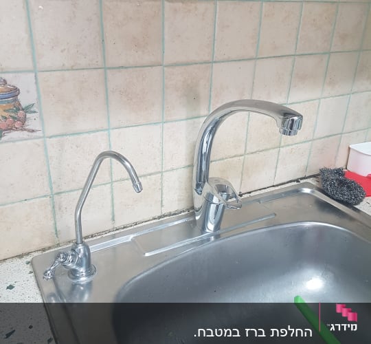 ברזים נירוסטה מעל כיור מטבח עם מסננת